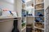 Elegant walk-in closet with organized shelves featuring towels, baskets, shoes, and an artistic California pillow.