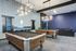 Chic game room featuring two billiards tables, modern lighting, and a cozy lounge area.