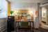 Charming workspace featuring a stylish desk with an array of decor, a microwave on a fridge, and a bright, open bathroom entrance.