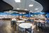 Spacious dining area with modern design, featuring circular and rectangular tables set against a stylish ceiling and vibrant walls.