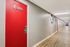 Bright corridor with red doors, modern lighting, and wood flooring leading to apartment C-306.