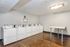 Bright and well-equipped laundry room with multiple washing machines on hardwood flooring.