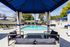 Luxurious outdoor pool area with elegant cabanas and lounging chairs, surrounded by lush green trees.