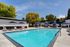 Elegant outdoor swimming pool with stylish lounge chairs and cabanas under blue skies.