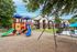 Inviting apartment complex with vibrant playground and lush greenery.