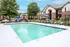 Inviting apartment outdoor pool area with lounge chairs, umbrellas, and a play area.