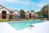 Charming apartment complex featuring a pristine pool and inviting lounge chairs under blue umbrellas.