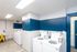 Bright and modern laundry room with white appliances and a bold blue accent wall.