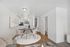 Elegant modern living space featuring a round dining table with four chairs, a cozy seating area, and a view of a contemporary kitchen.