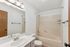 Bright and modern bathroom featuring a clean vanity, large mirror, and a cozy bathtub-shower combo.
