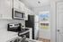 Contemporary kitchen with sleek white cabinets, stainless steel appliances, and a window view.