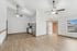 Bright open-concept living space with modern kitchen, large window, and ceiling fans.