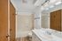 Modern bathroom featuring a sleek vanity, elegant lighting, and a spacious bathtub with wood accents.