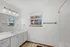 Spacious bathroom with sleek white cabinetry, large mirror, and a window offering natural light.