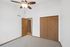Bright and airy bedroom with ceiling fan, wood closet doors, and plush carpet flooring.