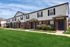 Charming row of modern townhouses with brick exteriors, lush green lawns, and clear blue skies.