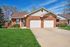 Attractive brick suburban house with a double garage and manicured lawn on a sunny day.