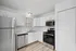 Contemporary kitchen with stainless steel appliances, white cabinetry, and hardwood flooring.