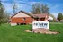 Charming brick apartment with front deck at ReNew Edwardsville in a lush, green setting.