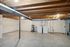 Bright, open basement featuring laundry appliances and water heater with exposed ceiling beams.
