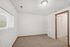 Inviting empty bedroom with plush carpeting, white walls, and ample natural light from a large window.