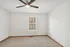 Well-lit empty room with a ceiling fan and large window.