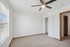 Inviting bedroom with soft carpet flooring, ceiling fan, and ample natural light.