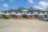 Charming two-story apartment complex with brick and white siding, featuring neat landscaping and paved parking.
