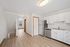 Contemporary kitchen with sleek white cabinetry, stainless steel appliances, and open living space.