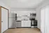 Contemporary kitchen with stainless steel appliances, white cabinetry, and wooden flooring.