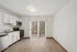 Modern kitchen with white cabinets and stainless steel appliances next to a dining area with sliding glass doors.