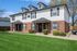 Beautifully maintained duplex with brick and siding exterior, lush green lawn, and stylish black shutters.