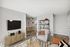 Inviting living room with modern decor, featuring a comfy armchair, sophisticated shelving, and a view of the dining area.