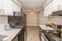 Modern kitchen with sleek black appliances, white cabinets, and a wood-look floor.