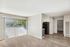 Sunlit living area with large window, carpeted floor, and open view to the kitchen space.