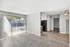 Well-lit apartment interior featuring wooden floors, large sliding glass doors, and a compact kitchen area.
