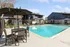 Inviting outdoor pool area featuring chaise lounges, umbrellas, and comfortable seating, set against a modern apartment backdrop.