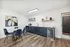 Sleek kitchenette featuring navy cabinetry, open shelving with plants, and a cozy dining area with modern artwork.