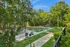 Serene outdoor park with lush greenery and modern seating area surrounded by tall trees.
