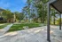 Beautiful outdoor area featuring manicured lawns, a modern pergola, and abundant trees under a clear blue sky.