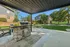 Outdoor patio with modern grill and seating area, surrounded by lush landscaped greenery and residential buildings.