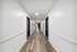 Contemporary apartment hallway with clean white walls and elegant wood flooring.