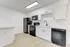 Modern kitchen with sleek white cabinets, black appliances, and marble countertops.