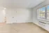 Spacious, modern living room with light wood flooring and large windows inviting natural light.