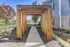 Charming wooden archway leading to a modern building, surrounded by lush garden landscaping.
