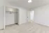 Spacious bedroom with an open closet and soft carpet flooring, capturing a minimalist design.