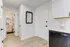 Bright entryway leading to a modern bathroom and kitchen with a sleek black dishwasher and marble countertop.