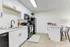 Bright and modern kitchen with white cabinetry, black appliances, and a breakfast bar.