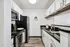 Modern kitchen with white cabinets, stainless steel appliances, and dark countertops.