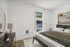 Bright bedroom with a modern bed, large window, stylish dresser, and contemporary artwork.